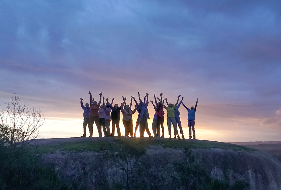 A group of people silhouetted standing on a hill