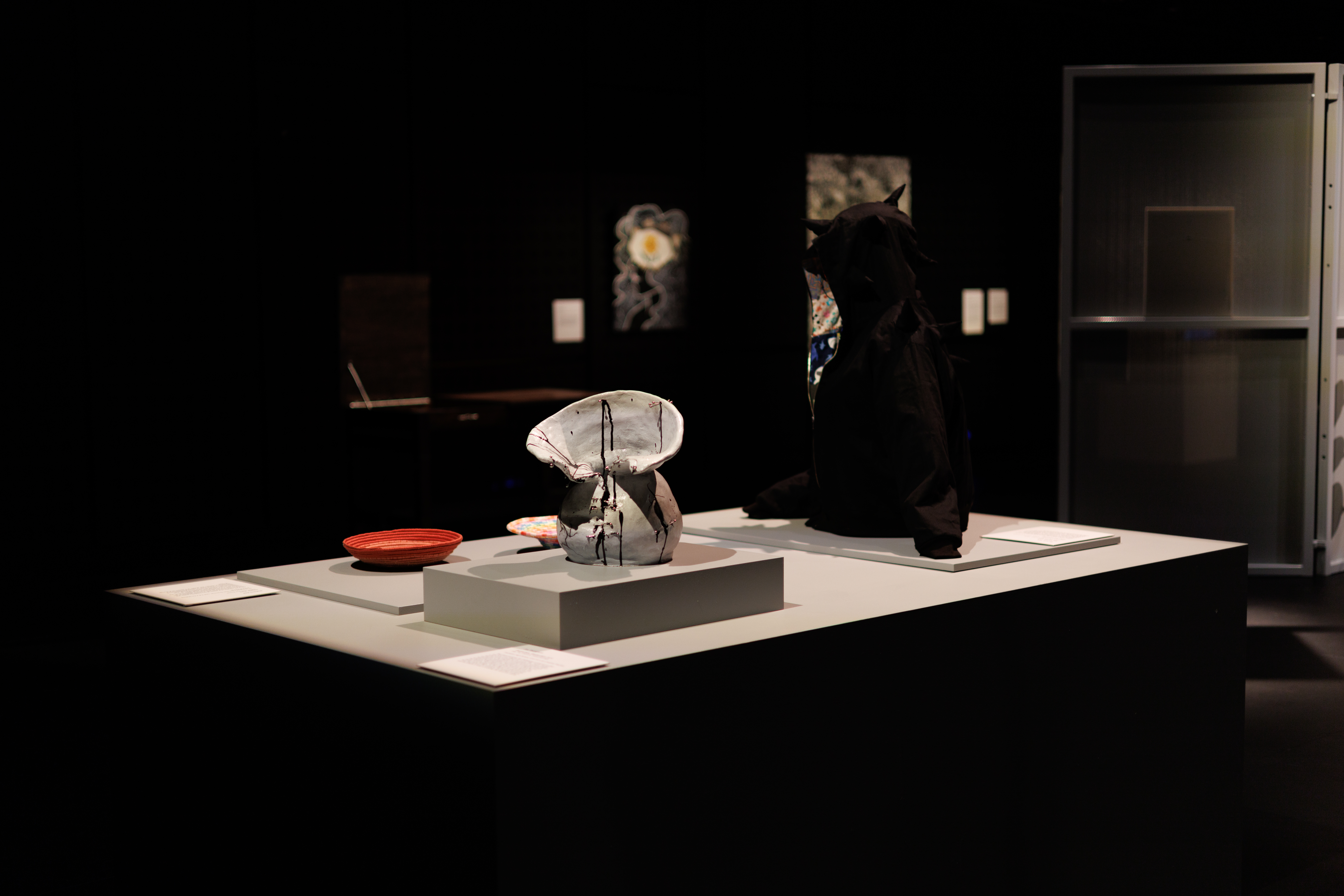 installation view of a display featuring a ceramic vase, a black hoodie and rope bowls