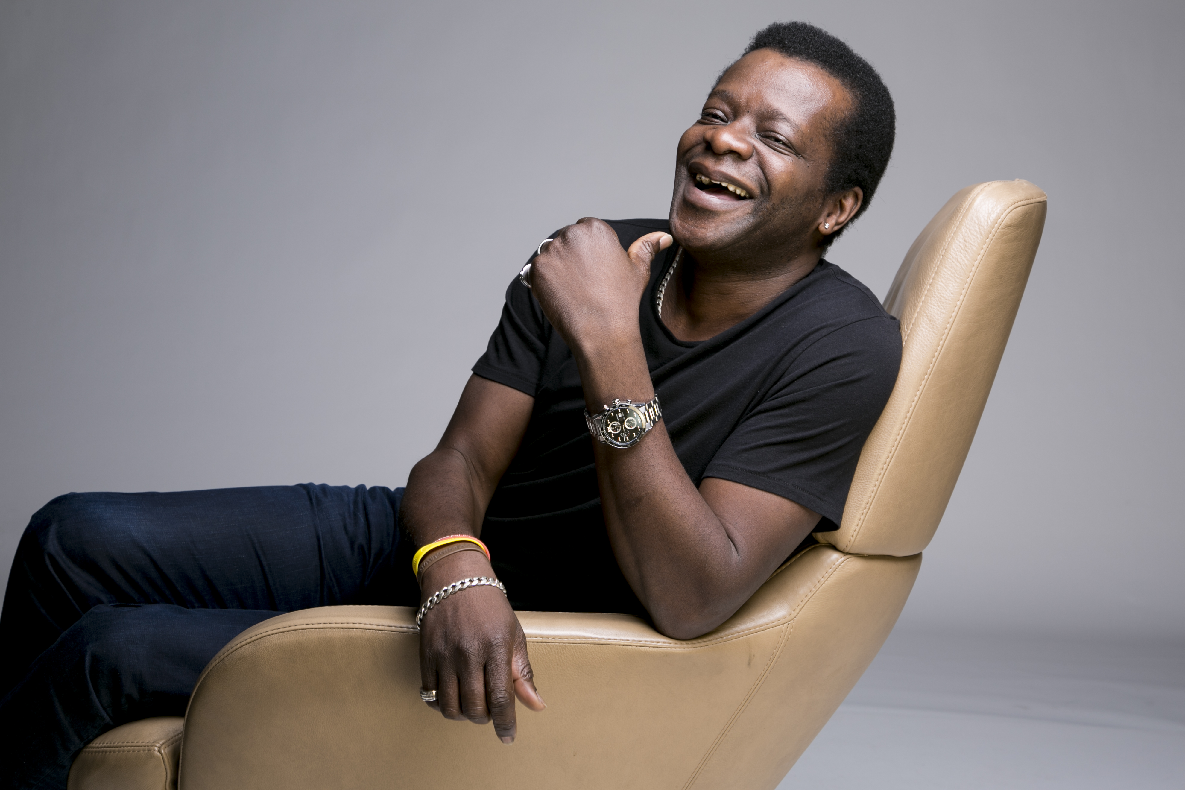 A man leans back in a chair, laughing. 