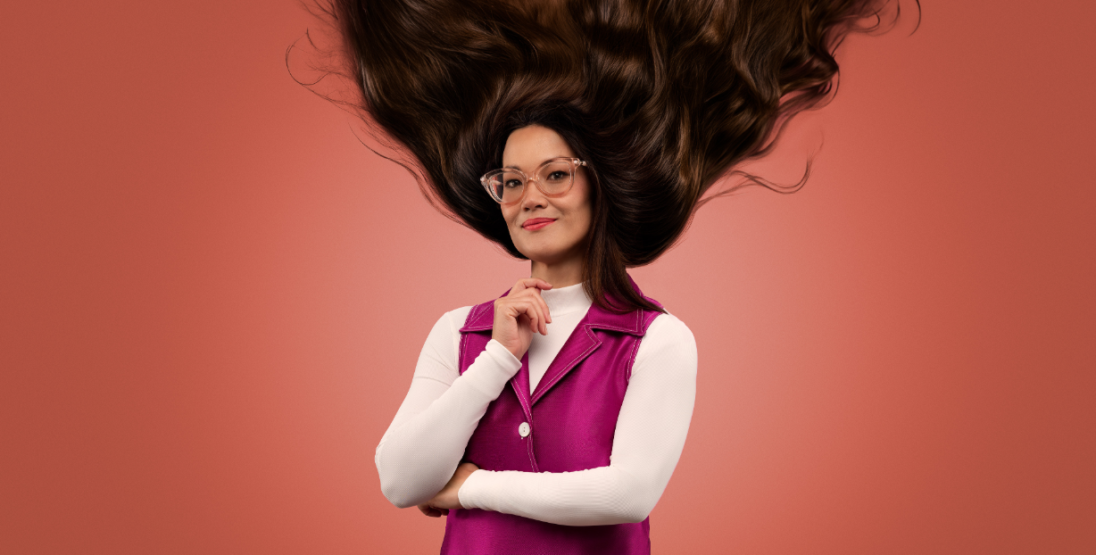 Lizzy Hoo wears a long steeve top and pink dress. Her hair is standing up.