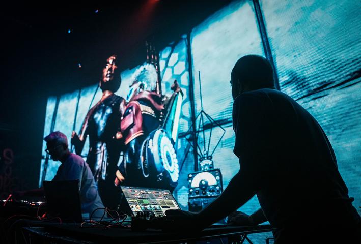 A dj in silhouette against a bright lit digital background