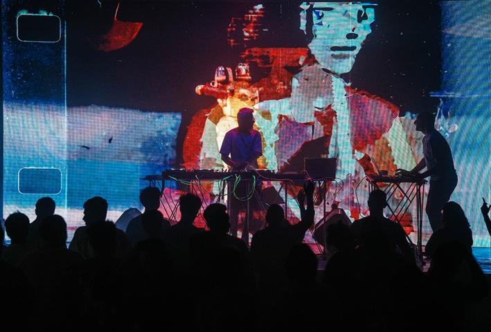 DJ's in silhouette against a bright lit digital background