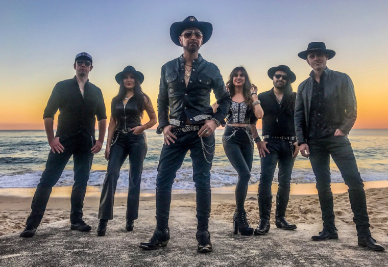 Six people in dark clothing stand against a bright sunset - members of Pseudo Echo