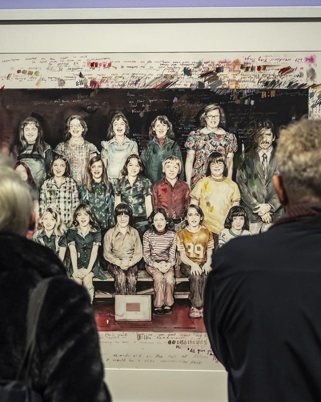 Two people look at an artwork on the wall