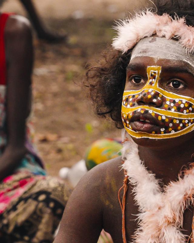 A young indigenous child wears traditional body paint