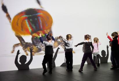 children dancing in front of a large projection of a spider