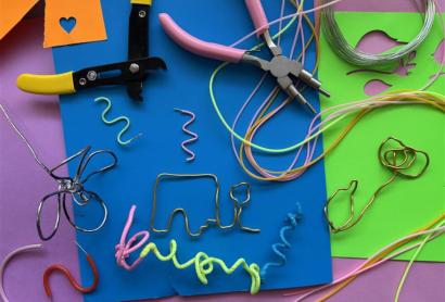 Flatlay of wire and pliers with purple blue and green coloured paper in the background