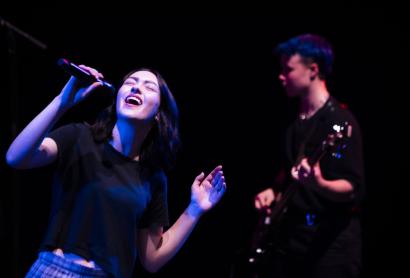 Young singer with a microphone and guitarist in the background