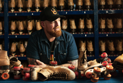 A man in a cap is surrounded by rollerskates.